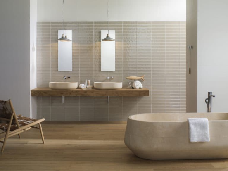 Béžová koupelna s lesklým béžovým obkladem, dlažba s imitací dřeva, mramorová vana do prostoru, umyvadla na dřevěné desce