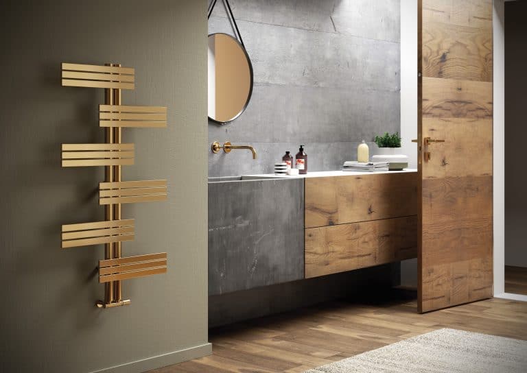 Koupelna s imitací betonu na zdi, dřevěný rustikální nábytek, zlatý designový radiátor, kulaté zrcadlo