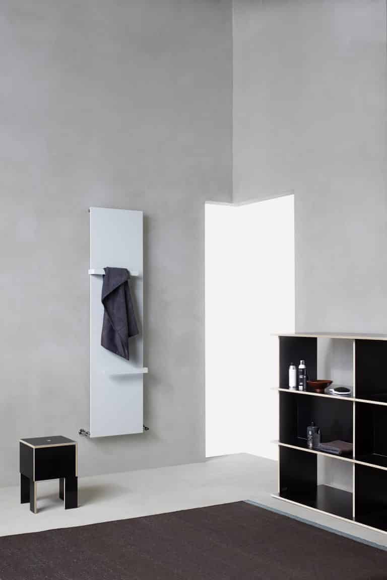 Betonová stěrka v koupelně, radiátor s držákem na ručník, černá stolička, černý regál