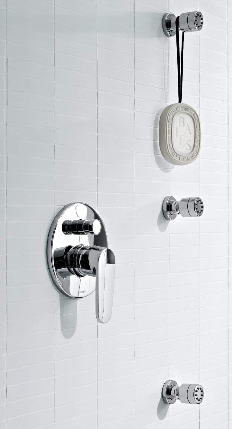 Sprchová baterie, boční masážní trysky, zavěšené mýdlo, bílý obklad na zdi