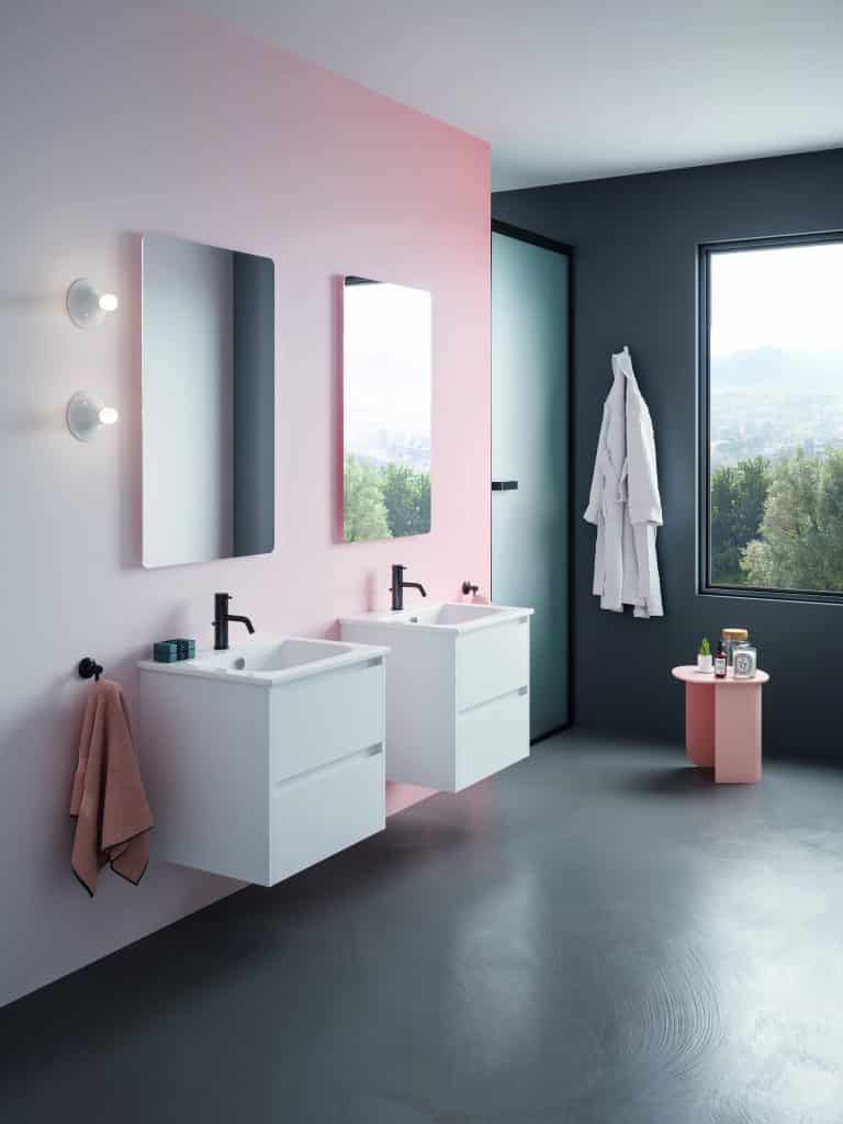 Koupelna s růžovou stěnou, šedá podlaha, dvě umyvadlové skříňky s umyvadly a černou baterkou