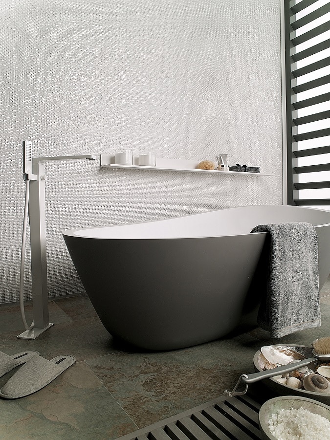 Koupelna s bílým lesklým obkladem mozaikou, černá vana do prostoru s chromovou baterií z podlahy, šedá dlažba