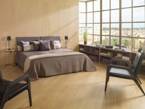 Ložnice s obkladem dřeva a dřevěnou podlahou, prosklená stěna, hnědá postel, hnědá křesla