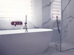 Mramorová koupelna s vanou do prostoru, měděná vodovodní vanová baterie, skleněný sprchový kout