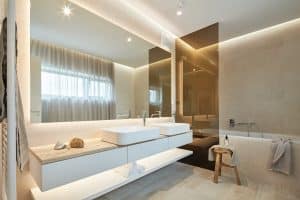 Koupelna s dlažbou v dekoru dřeva, mramorová deska pod umyvadlem, umyvadla na desce, vana se skleněnou zástěnou, dřevěná stolička