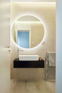 Koupelna s kulatým zrcadlem, umyvadlo na dřevěné desce, chromový radiátor