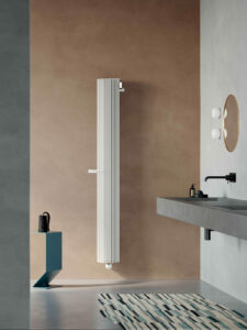 Bílý designový kulatý radiátor v koupelně s držákem na ručník